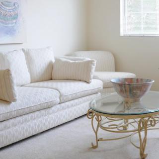 A cozy living room with a white sofa and a glass coffee table.