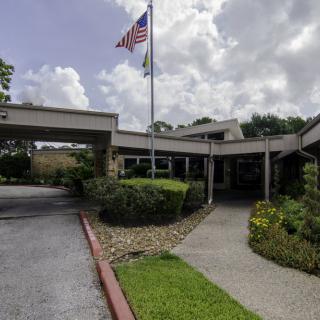A building entrance with a flagpole and landscaped garden.
