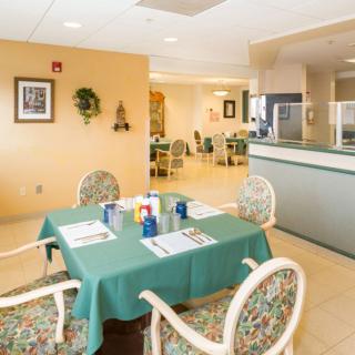 A cozy dining area with neatly arranged tables and chairs, decorated with greenery and wall art.