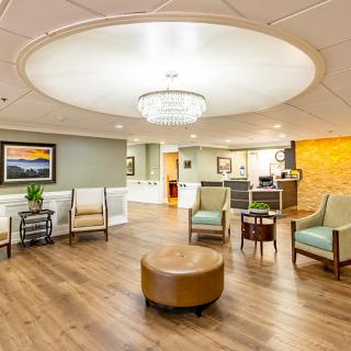 A modern lobby with comfortable seating and a central chandelier.