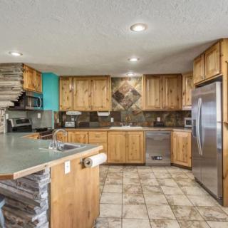A spacious kitchen featuring wooden cabinets, tile flooring, and stainless steel appliances.