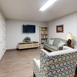A cozy living room featuring a green sofa, a television, and decorative elements.