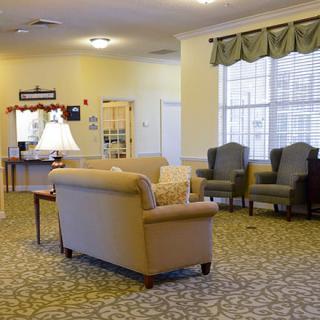A cozy living room with a sofa, chairs, and a lamp on a carpeted floor.