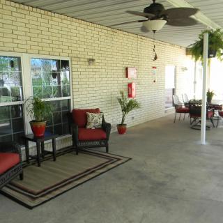 A cozy outdoor patio area with comfortable seating, plants, and a ceiling fan.