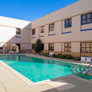 A serene swimming pool surrounded by modern architecture, perfect for relaxation on a sunny day.