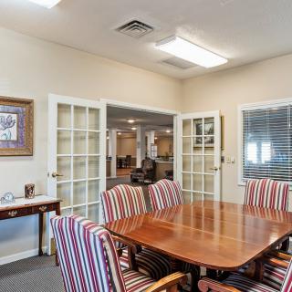 A conference room with a wooden table and striped chairs, separated by glass doors.