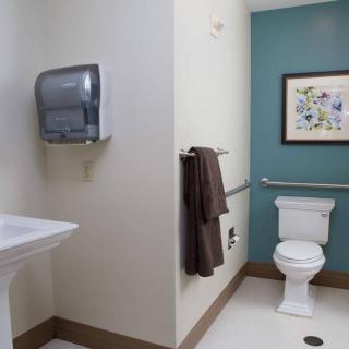 A clean and well-organized bathroom with a toilet, sink, and wall art.