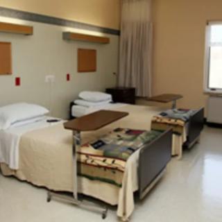 A hospital room with two neatly made beds and basic amenities.