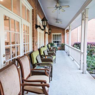 A cozy porch with cushioned chairs and ceiling fans, perfect for relaxation.