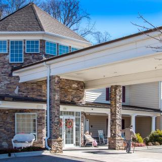 A residential building with a stone facade and covered entrance on a sunny day.