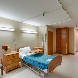 A well-organized hospital patient room featuring a bed, nightstand, and adequate lighting.