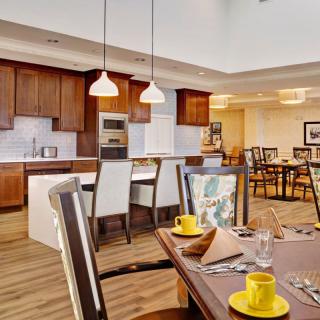 A modern kitchen and dining area featuring wood cabinets and an open layout, with stylish pendant lighting and elegant furniture.