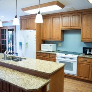 A modern kitchen with wooden cabinets and a granite countertop island.