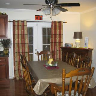 A cozy dining room with a table set for six, featuring wooden chairs and elegant curtains by the French doors.
