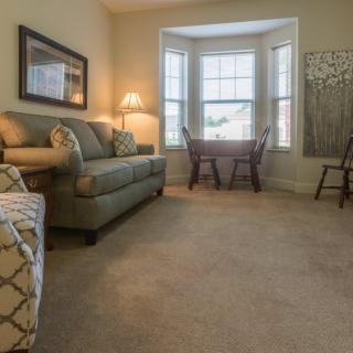 A cozy living room with a sofa, table, chairs, and a large window.