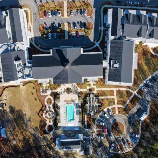 Aerial view of a complex with buildings, a swimming pool, and surrounding pathways.