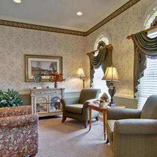 A traditionally decorated living room featuring comfortable armchairs, a floral sofa, and soft lighting.