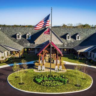 A large building with a circular driveway and an American flag in the foreground.