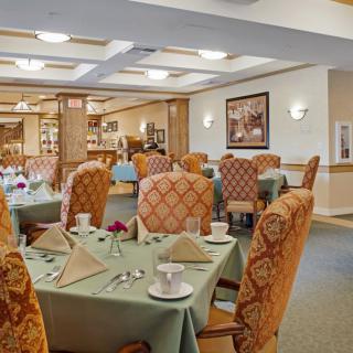 A cozy dining room with neatly set tables and upholstered chairs.