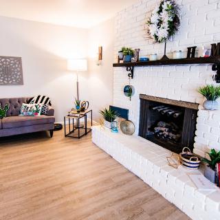 A cozy living room with a modern white brick fireplace, stylish decor, and wooden flooring.