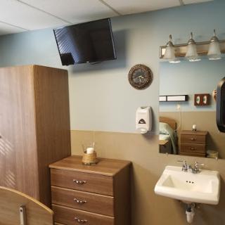 A well-furnished hospital room featuring a television, wash basin, and decorative elements.