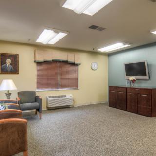A cozy waiting room with seating, a television, and soft lighting.