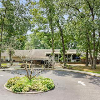 A charming residential house surrounded by lush greenery and a circular driveway.