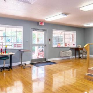 A spacious room in a rehabilitation center with exercise equipment and wooden flooring.
