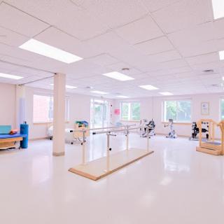 A spacious physical therapy room designed for rehabilitation, featuring exercise equipment and natural light.