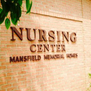 Sign for Mansfield Memorial Homes Nursing Center on a brick wall.
