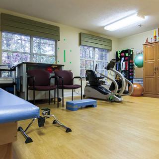 A rehabilitation exercise room with fitness equipment and therapy tools.