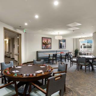 A modern gaming room featuring a poker table with cards and chips, complemented by stylish seating and contemporary decor.
