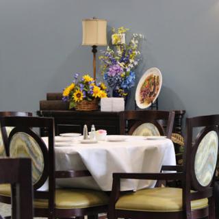 A beautifully arranged dining area featuring a table set for meals, adorned with fresh flowers and elegant decor.