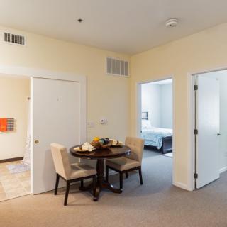 A cozy dining area in an apartment with a view into a bedroom.