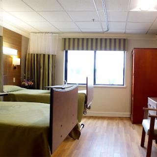 A well-lit hospital room featuring two beds, designed for patient comfort and care.