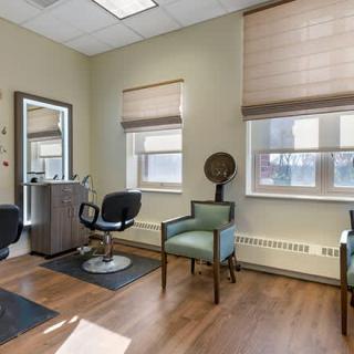 A well-lit hair salon with chairs, a mirror, and wooden flooring.