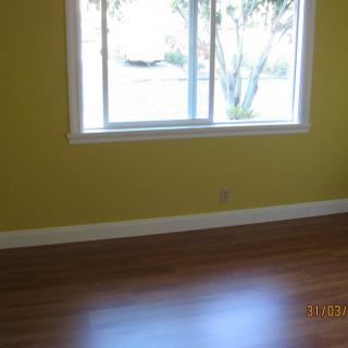 A bright, empty room with yellow walls and a hardwood floor.