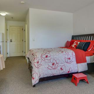 A cozy bedroom interior featuring a bed with floral bedding and vibrant pillows.