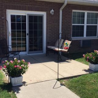A welcoming outdoor patio area with vibrant flowers and a comfortable bench.