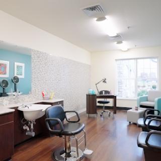 A modern and well-lit hair salon interior, featuring styling chairs and a workstation.