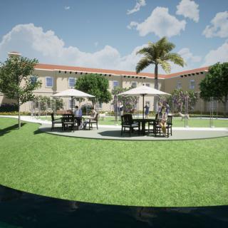 A sunny courtyard with outdoor furniture and umbrellas on a green lawn, surrounded by buildings and palm trees.
