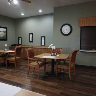 A cozy restaurant interior with neatly arranged tables and chairs, adorned with a wall clock and framed art.