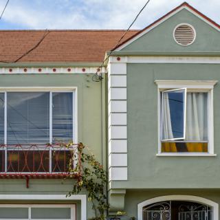 A charming residential house with a green facade and distinctive windows.