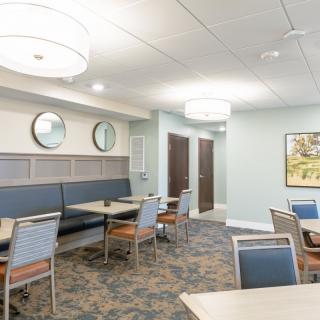 A modern dining area with neatly arranged tables and chairs, featuring contemporary lighting and decor.