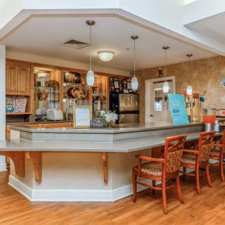 A cozy bar area with a wooden counter and seating, featuring warm lighting and inviting decor.