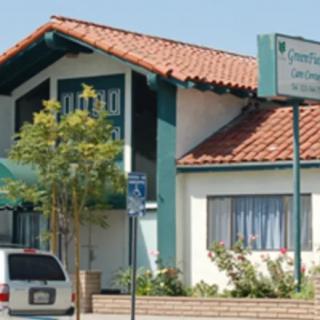 A quaint motel with a red-tiled roof and parking area.