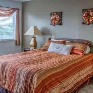 A cozy bedroom with warm-toned bedding and a lamp by the window.