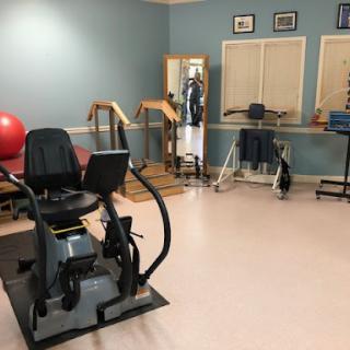 A well-equipped exercise room designed for rehabilitation and physical therapy, featuring various fitness equipment including an exercise ball and workout machines.