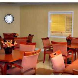 A cozy dining area with wooden tables and chairs, adorned with floral centerpieces and a wall clock.