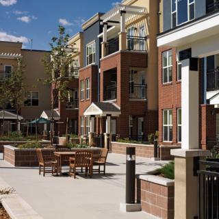 A modern apartment complex with outdoor seating and landscaped areas.